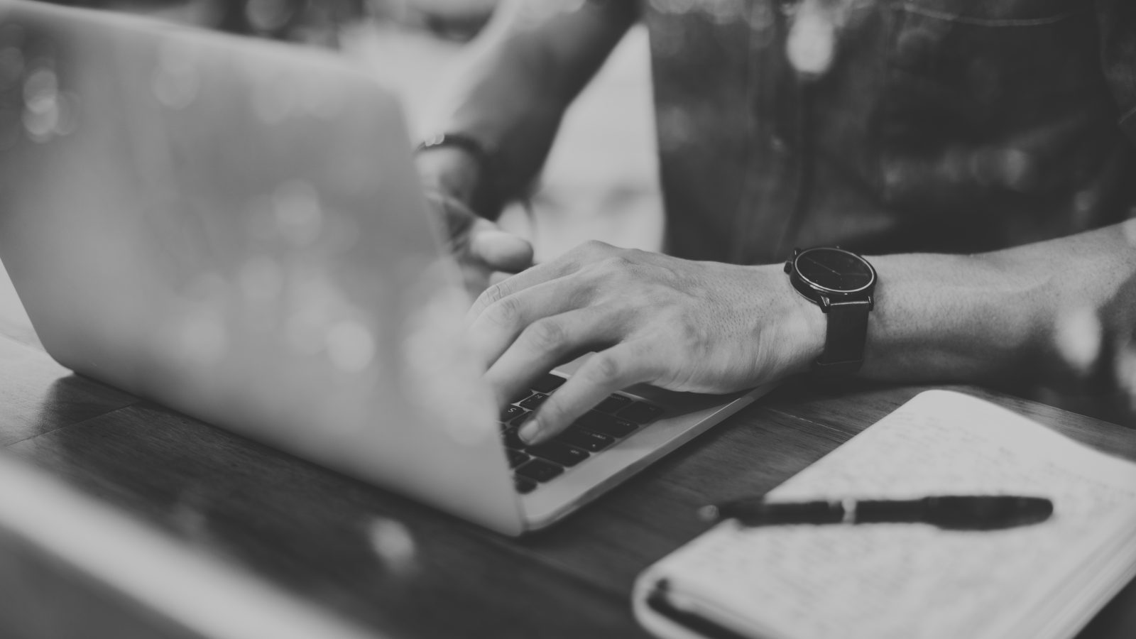 Closeup of man using laptop in cafe grayscale